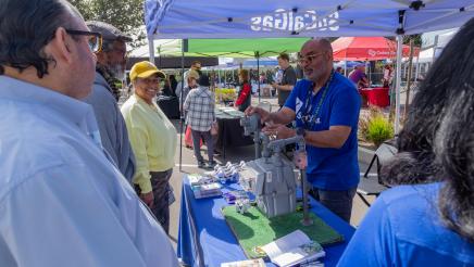 SoCalGas staffer at booth, discussing gas meter with attendees